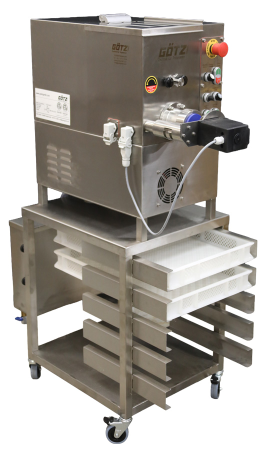 A side angled view of the P-10-G Pasta Extruder on top of a stainless steel cart with two pasta baskets.